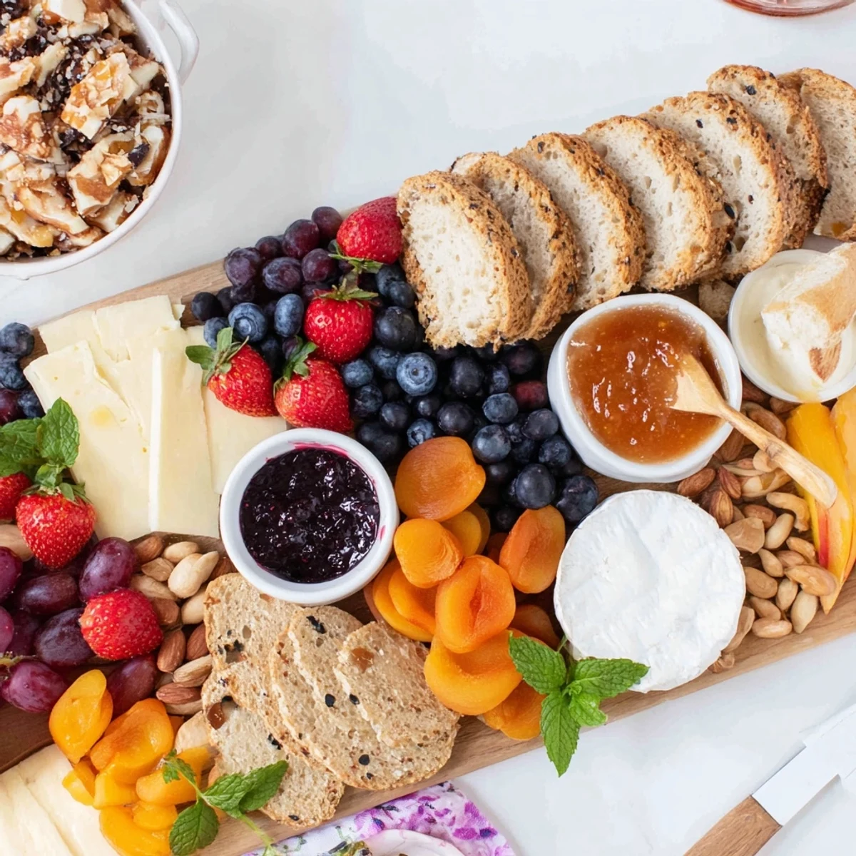 A colorful jam-infused brunch board displaying fresh fruits, cheeses, and breads.  