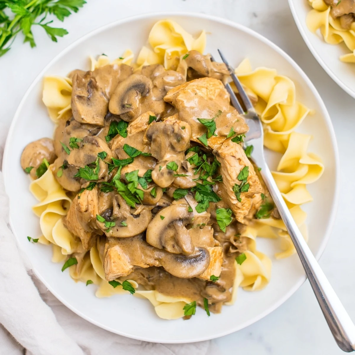 Creamy Chicken Stroganoff served over buttery egg noodles, garnished with fresh parsley.  