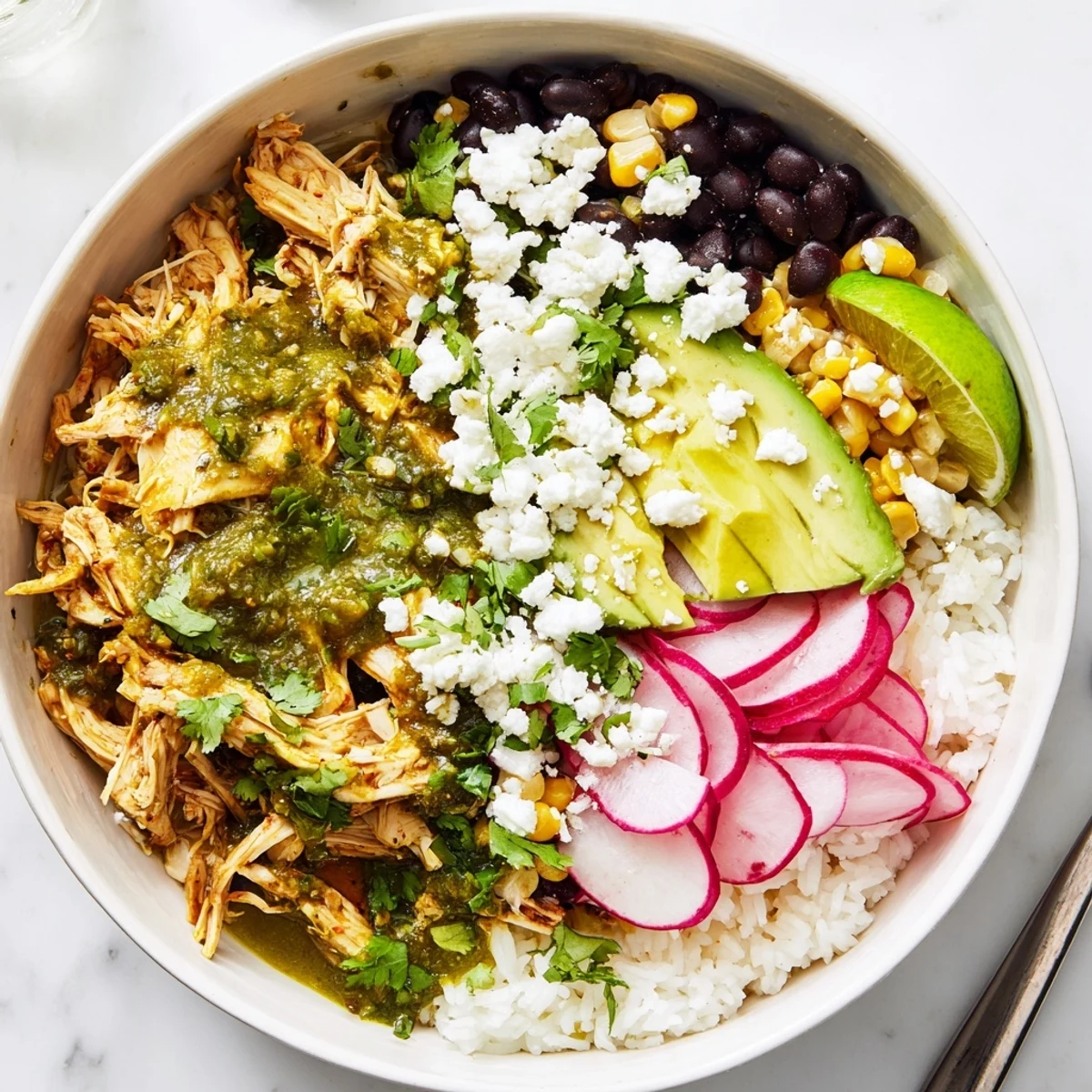 Zesty green enchiladas rice bowl filled with chicken, beans, and colorful toppings.  