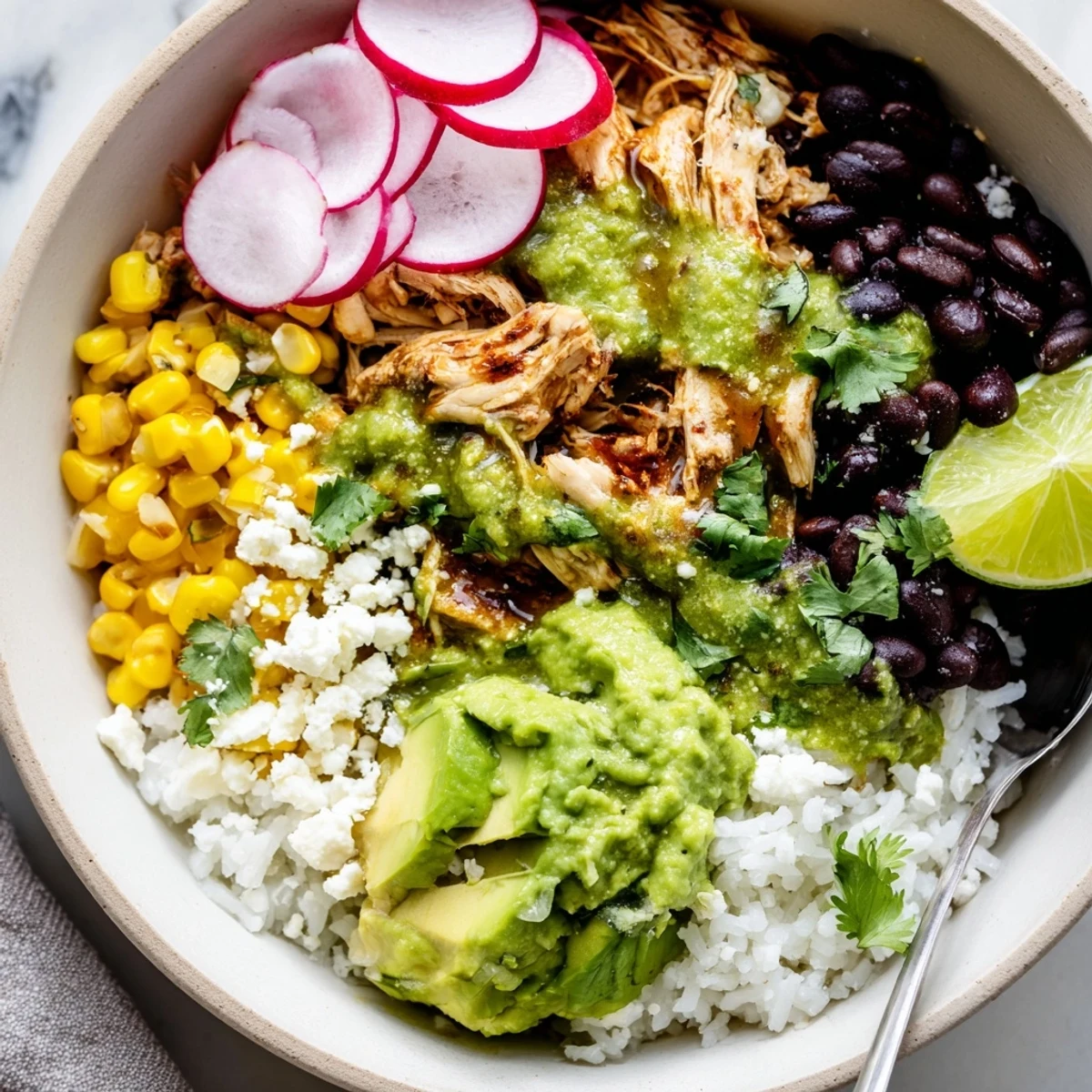 Delicious green enchiladas rice bowl garnished with radishes, lime, and queso fresco.