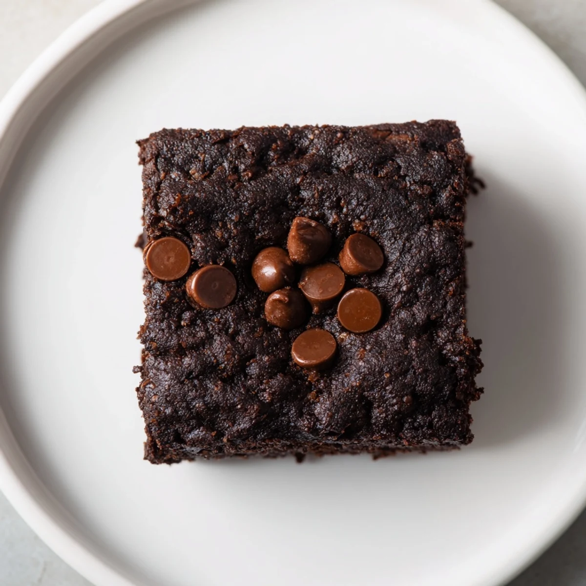 Fudgy black bean brownies, warm from the oven, with a scattering of melted chocolate chips.