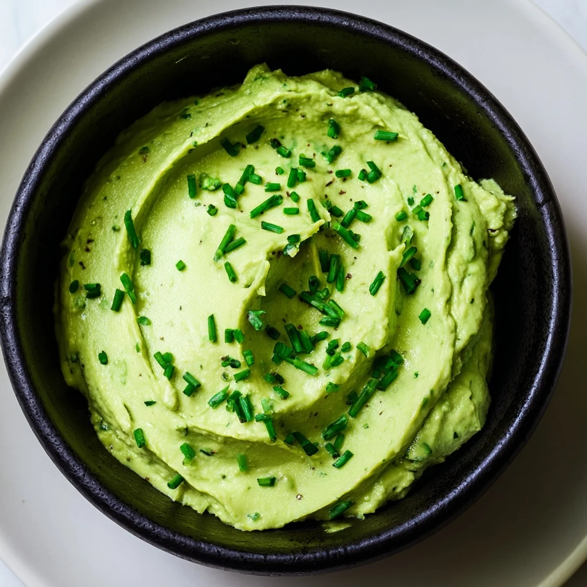 Creamy green Witch's Brew Cauldron dip with dark, smoky accompaniments for a spooky Halloween appetizer.