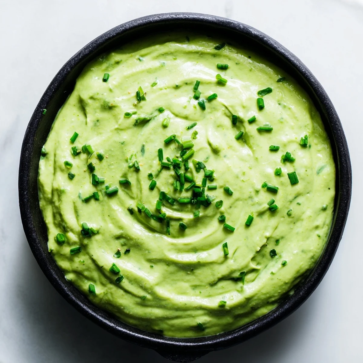 A vibrant Witch's Brew Cauldron, in a black bowl, surrounded by dark grapes and chips for dipping.