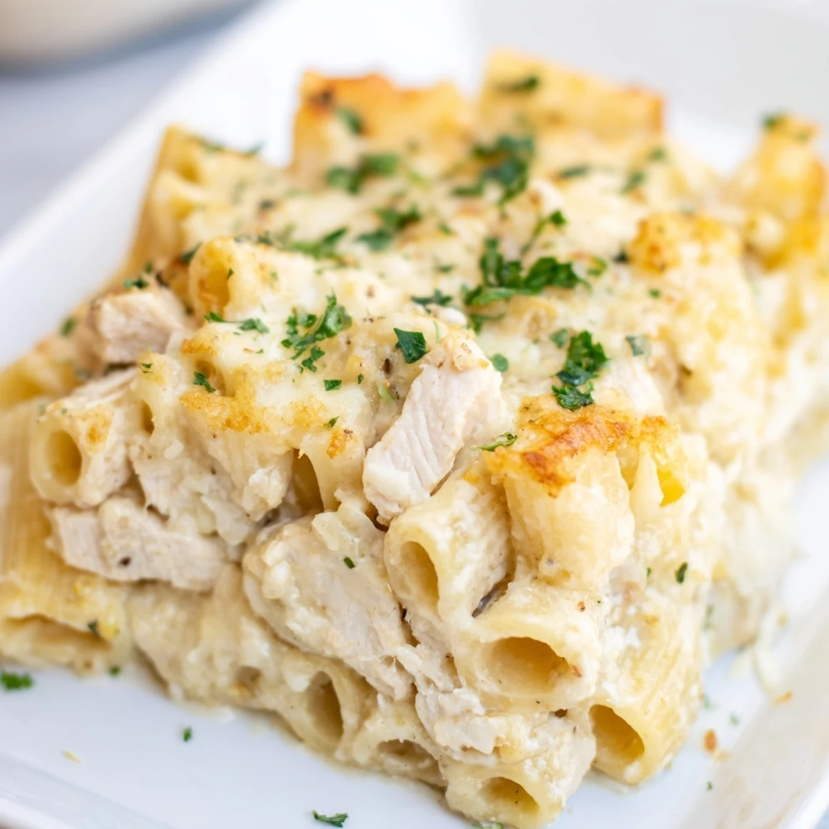 Golden-brown Chicken Alfredo Bake bubbling in a casserole dish, ready to serve with parsley.