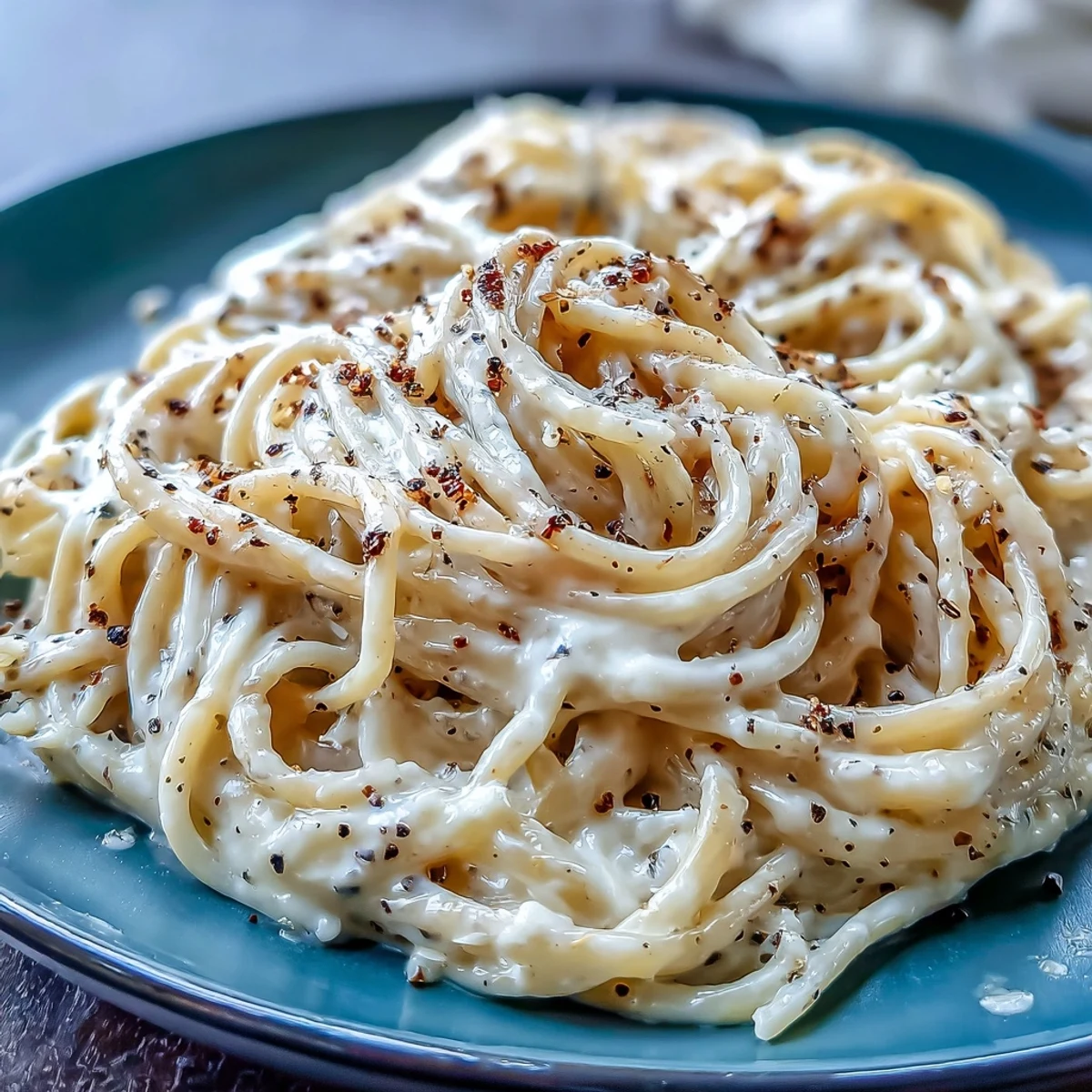 Al dente spaghetti coated in a creamy, peppery Cacio e Pepe sauce, served steaming in a white bowl.