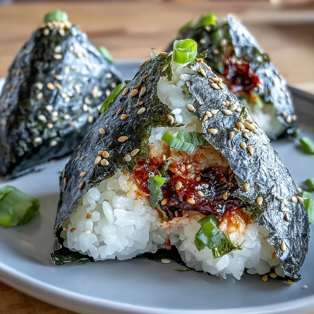 An overhead view of a plate of spicy tuna onigiri, garnished with sesame seeds and ready for a quick Japanese-inspired snack.