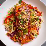 A beautifully arranged teriyaki salmon bowl, showcasing the vibrant colors of Asian slaw.