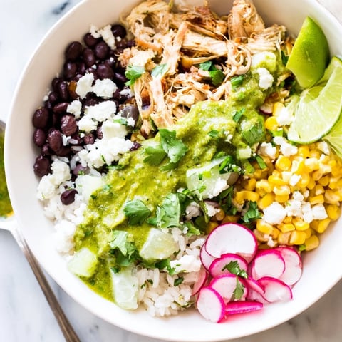 Vibrant green enchiladas rice bowl topped with fresh avocado and cilantro.  