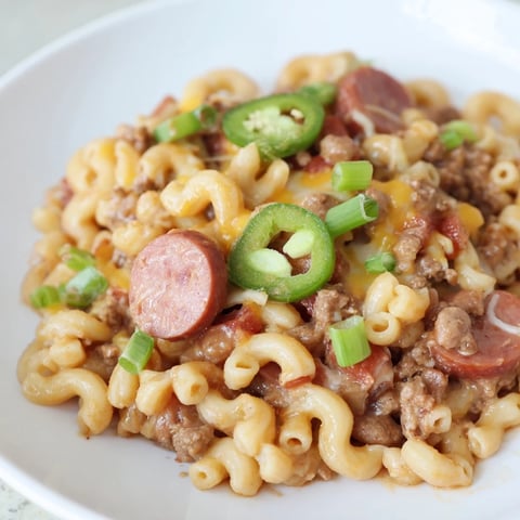 A bubbly dish of Chili Cheese Dog Mac & Cheese, with a golden, cheesy crust on top.