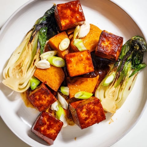 Golden brown Miso-Glazed Tofu & Winter Squash alongside vibrant green bok choy, drizzled with savory sauce.