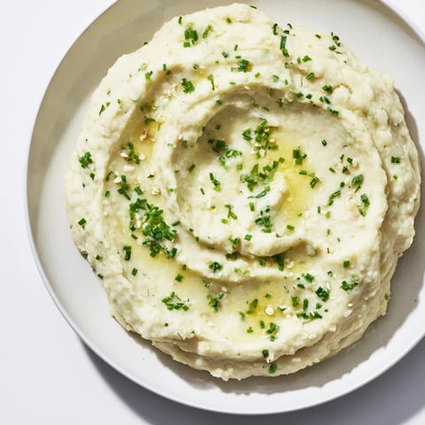 Creamy cauliflower mash with roasted garlic, herbs, and lemon, a vibrant, savory side.