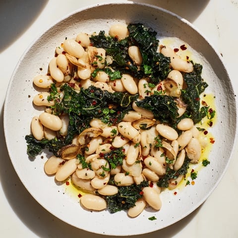 Steaming bowl of Garlicky Beans with Winter Greens, a hearty vegetarian main course ready to serve.