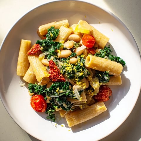 A steaming bowl of Healthy Tuscan White Bean & Kale Christmas Pasta, full of fresh ingredients.