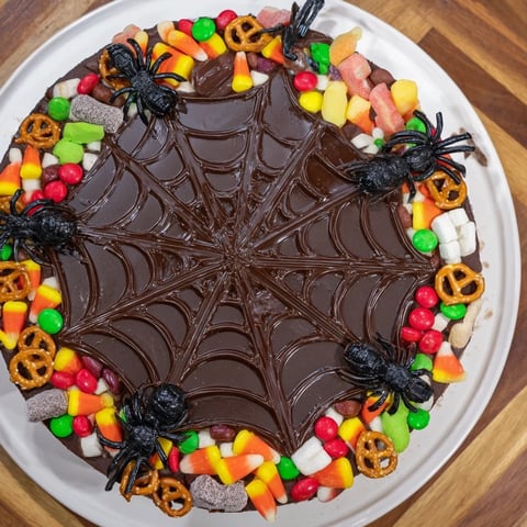 Arrangement of vibrant candies on a platter with dark chocolate spiderweb for fun Spiderweb Candy Platter.