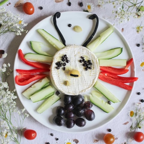 A colorful Coccinelle Amusante Planche Pique-Nique, with ladybug bell pepper "wings" and fresh veggie sides for a fun snack.
