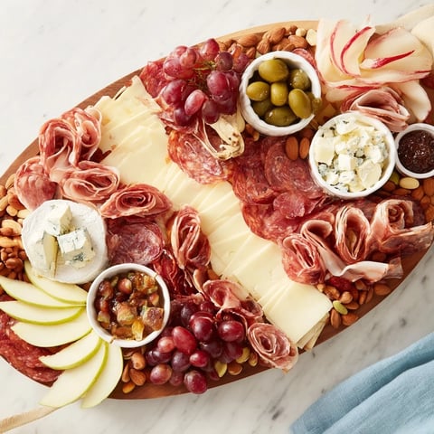 Elegant Gilded Edge cheese board: a vibrant presentation of cheeses, meats, fruits, and crackers, beautifully arranged.