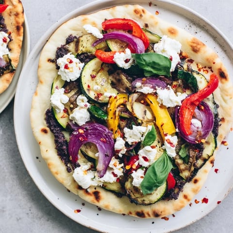 Naan bread pizza with vibrant roasted vegetables and creamy feta, a Mediterranean delight.