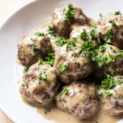 Golden-brown Swedish Meatballs swimming in a creamy, savory sauce, ready for mashed potatoes.