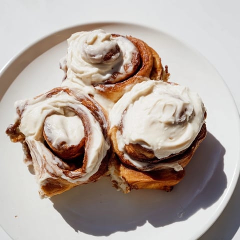Warm, golden Pumpkin Cinnamon Rolls, drizzled with creamy frosting and ready for a cozy breakfast.