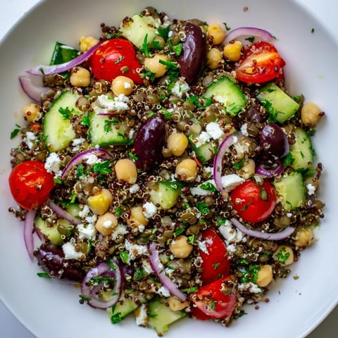 A vibrant Greek Power Salad with lentils, quinoa, chickpeas, and fresh vegetables tossed in zesty vinaigrette.