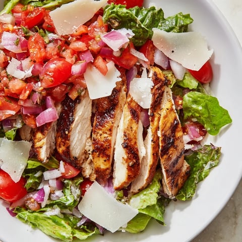 Freshly grilled chicken slices are topped with a vibrant tomato-basil mixture and served over crisp mixed greens for Bruschetta Chicken Salad.