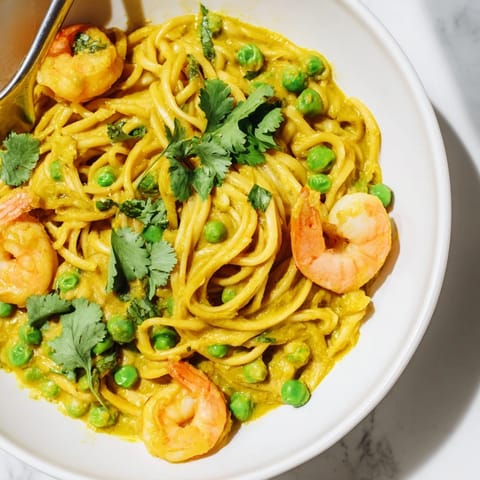Bright Yellow Curry Shrimp Pasta tossed with vibrant peas and fresh coriander.  