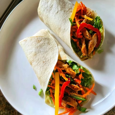 A close-up of a delicious and satisfying Teriyaki Chicken Wrap, perfectly rolled and ready to serve.