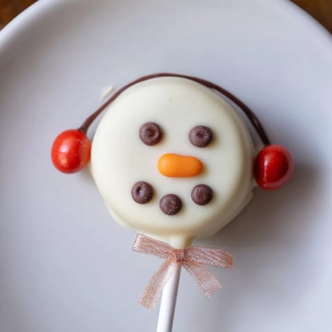 Adorable Budget-Friendly Oreo Snowman Pops, decorated with chocolate chips, ready to bring smiles to kids.