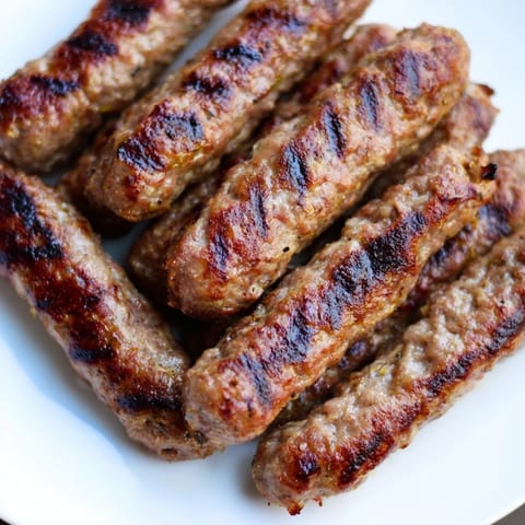 Smoky, grilled Romanian mici sausages with crispy edges, perfect for a summer cookout experience.