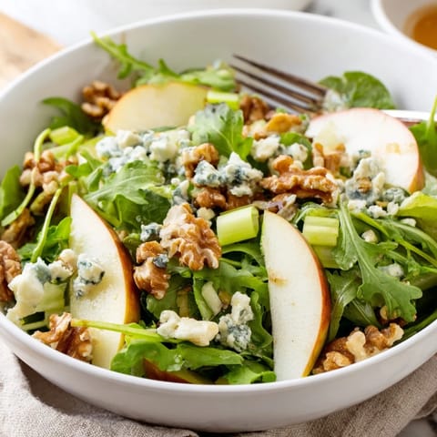 A vibrant Apple and Walnut Salad in a white bowl, drizzled with dressing and ready to serve as a refreshing side.