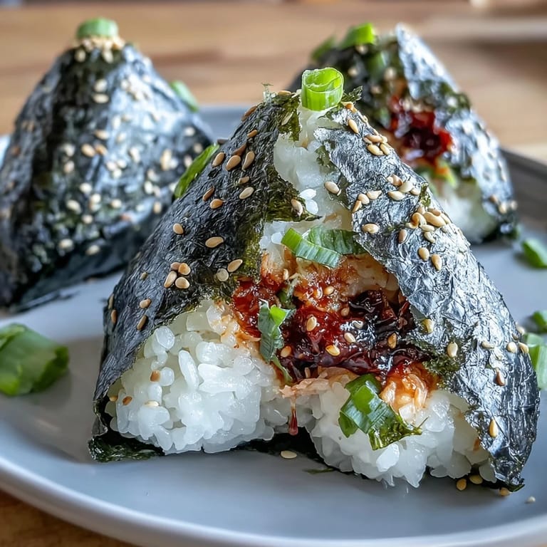 An overhead view of a plate of spicy tuna onigiri, garnished with sesame seeds and ready for a quick Japanese-inspired snack.