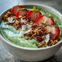 A vibrant strawberry matcha latte smoothie bowl with creamy matcha base and fresh strawberry slices.