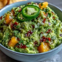 Vibrant Cinco de Mayo guacamole with mango and jalapeño, creamy avocado blended with sweet fruit and a spicy kick, perfect for parties.