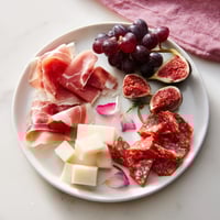 The Crimson Crest charcuterie board, filled with red meats, cheeses, and colorful garnishes.